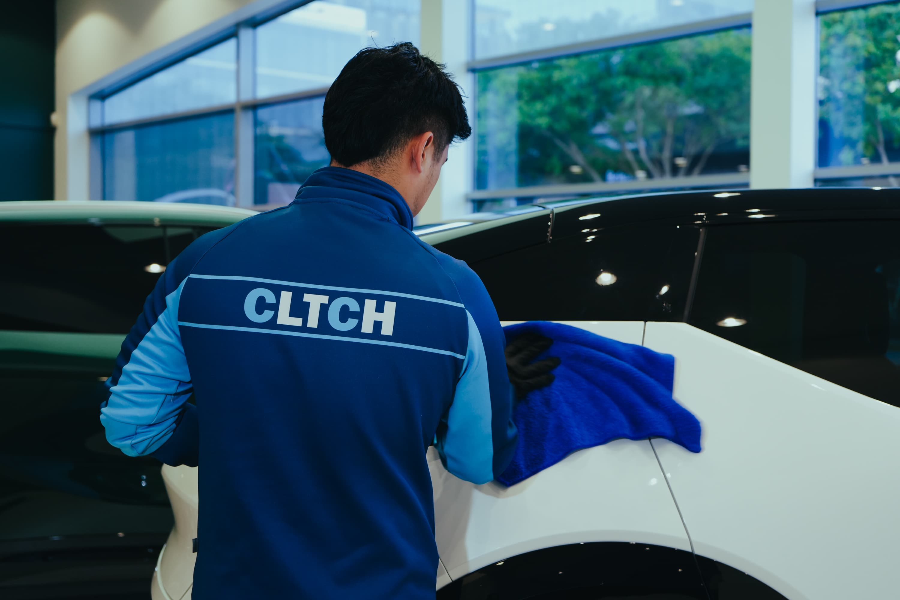 CLTCH technician detailing a vehicle in a dealership showroom