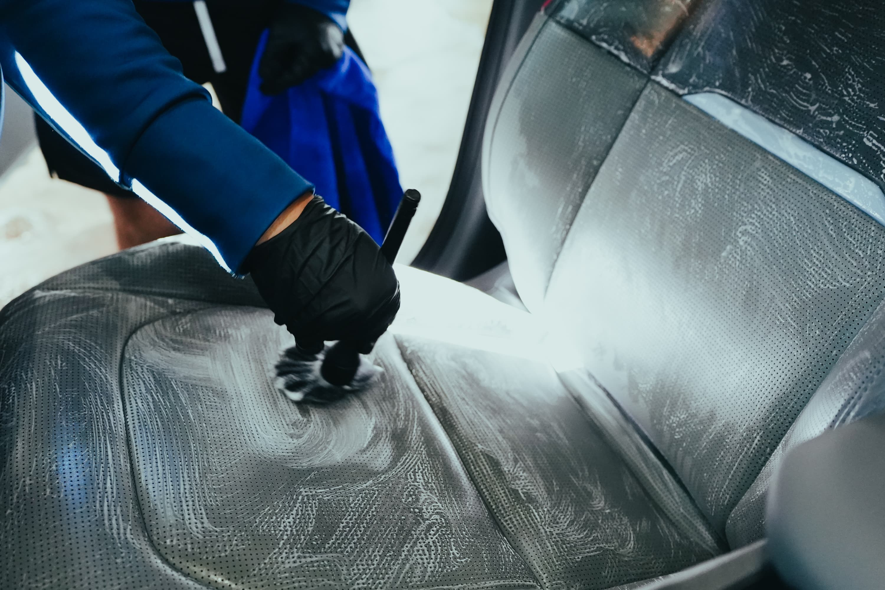 Leather seat being deep-cleaned with shampoo